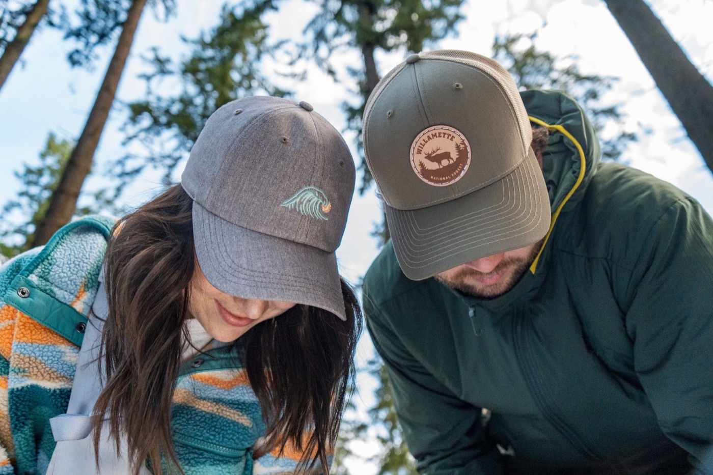 Two models in a wave cap and Willamette trucker looking down, shot from below