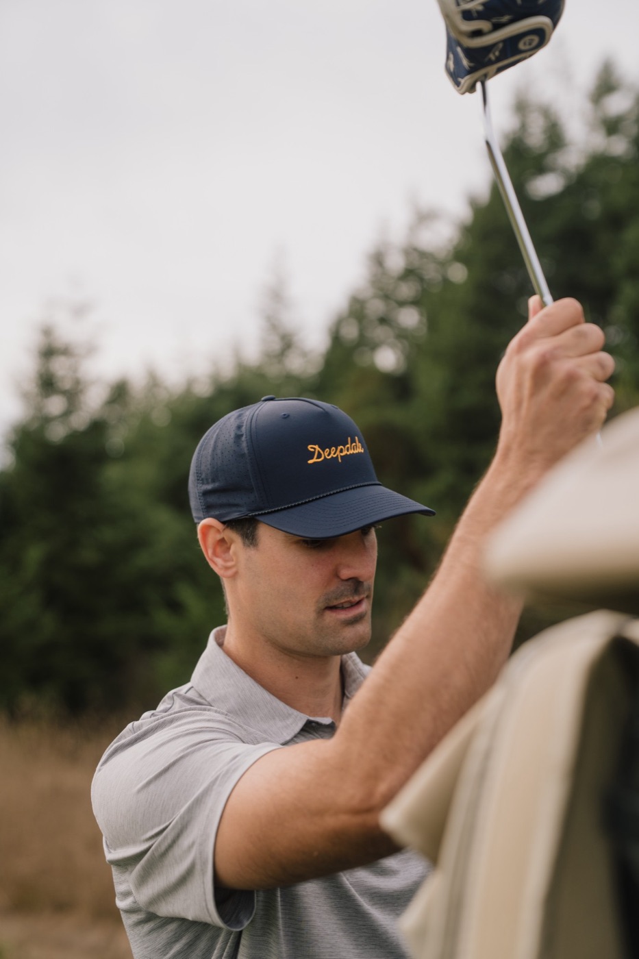 Golfer in a Deepdale cap pulling a club from his bag