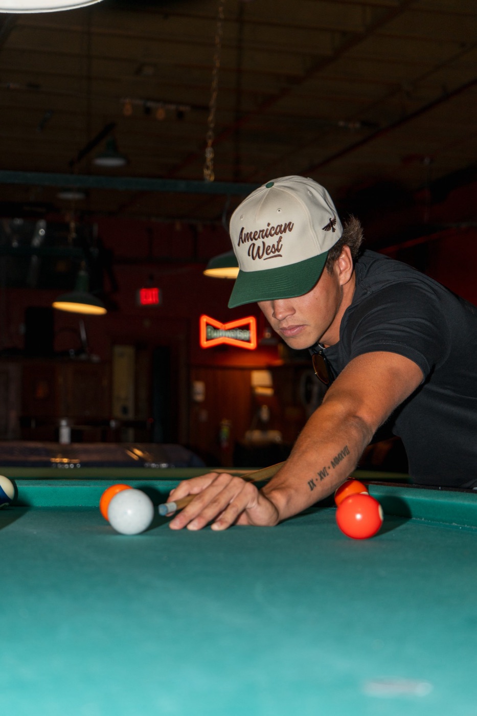 Model in an American West cap lining up a pool shot