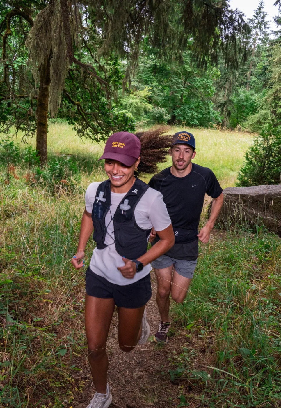 Two trail runners in Richardson caps running up a forest trail