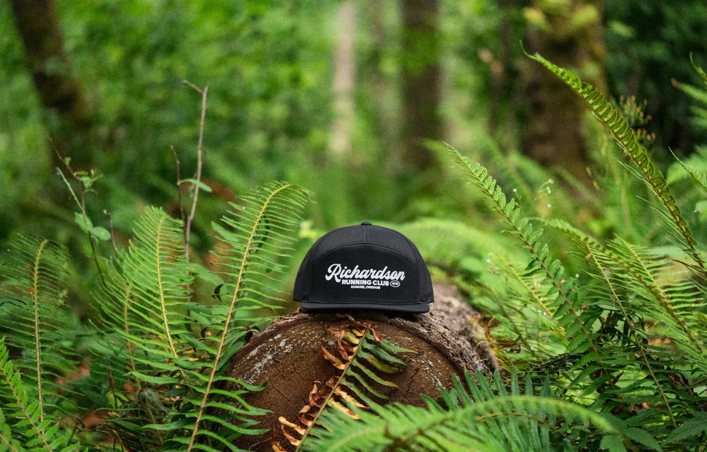 Richardson Running Club cap on a log among ferns