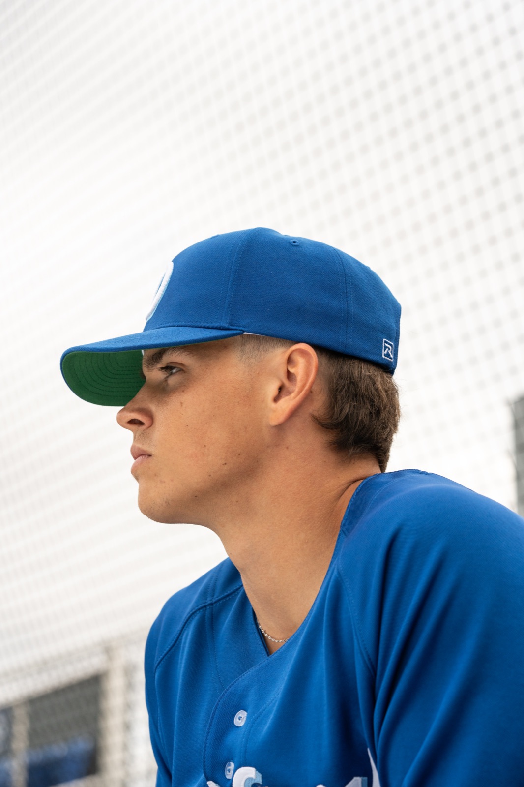 Baseball player in a blue Richardson cap in the dugout