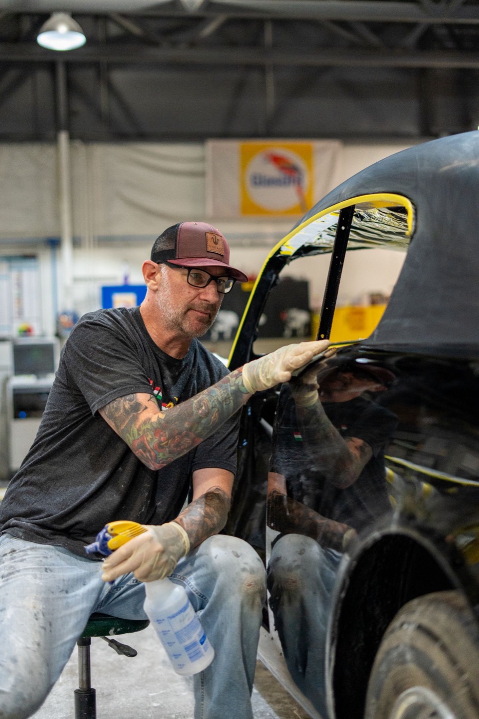 Restoration specialist in a Vintage Underground cap prepping a car body